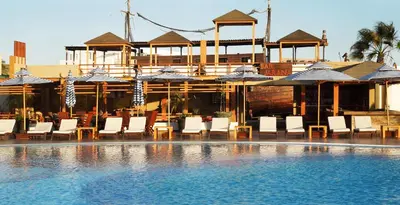 a pool with chairs and umbrellas in front of a building at Aranwa Paracas Resort & Spa in Paracas