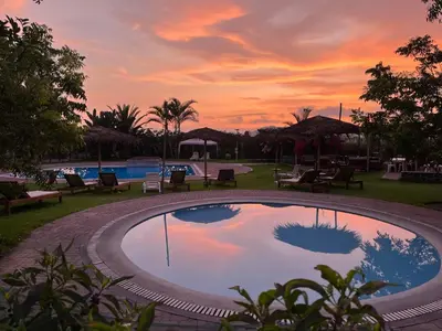 a large swimming pool with a sunset in the background at Bungalows de Casa Verde in Mala