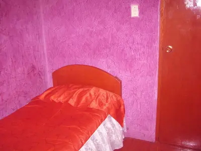 a bedroom with a red bed in a pink wall at Hospedaje Pumacurco Betty in Cusco