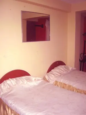 a bedroom with two beds and a mirror on the wall at Hospedaje Pumacurco Betty in Cusco