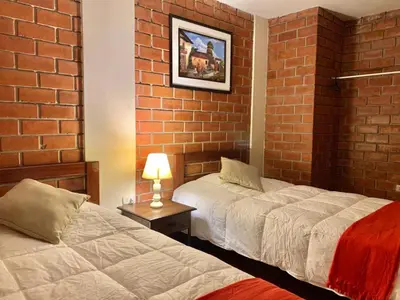 a bedroom with two beds and a brick wall at Hotel Colibri in San Vicente de Cañete