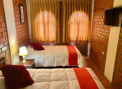 a hotel room with two beds and a television at Hotel Colibri in San Vicente de Cañete