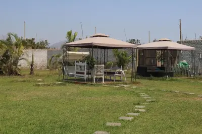 a yard with two umbrellas and a table and chairs at Los Naturales in Huaral
