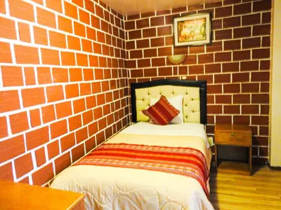 a brick walled bedroom with a bed in a room at Hostal Encanto Machupicchu in Machu Picchu