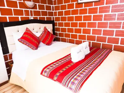 a bed in a room with a brick wall at Hostal Encanto Machupicchu in Machu Picchu