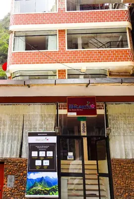 a bus stop with a sign in front of a building at Hostal Encanto Machupicchu in Machu Picchu