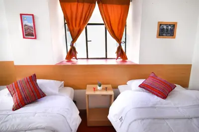 two beds in a room with a window at CASONA TORDO - A 3 Cdras de la Plaza - Habitaciones con baño privado in Cusco