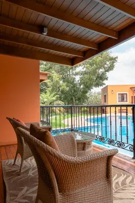 a balcony with wicker chairs and a view of a pool at Hotel & Hacienda La Caravedo in Ica