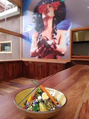 a bowl of vegetables on a wooden table with a painting at Las Qolqas EcoResort Ollantaytambo in Ollantaytambo
