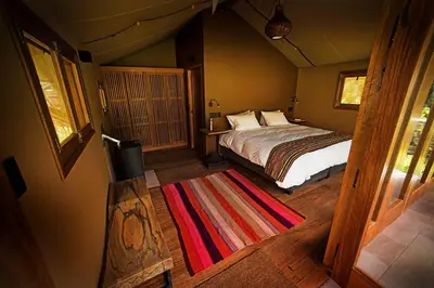 a bedroom with a bed and a rug on the floor at Las Qolqas EcoResort Ollantaytambo in Ollantaytambo