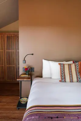 a bedroom with a bed and a table with a lamp at Las Qolqas EcoResort Ollantaytambo in Ollantaytambo
