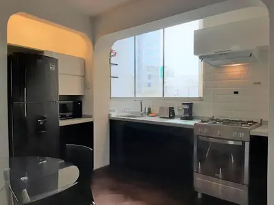a kitchen with black appliances and a large window at Miraflores Kennedy's Park Apartment in Lima