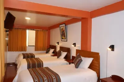 a hotel room with three beds and a television at Amakonkay Machupicchu in Machu Picchu