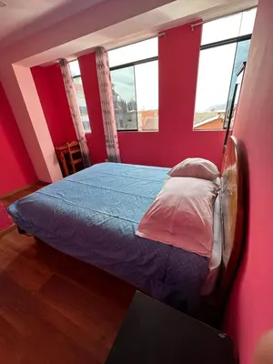 a bedroom with a bed in a room with red walls at Departamento Don Santiago Centro in Cusco