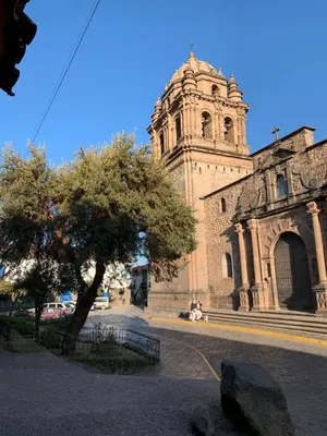 a building with a tower and a tree in front of it at Departamento Don Santiago Centro in Cusco