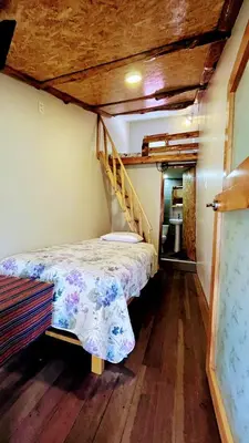 a small bedroom with a bed and a staircase at FRANKFURTER HOF FAMILIAR Oxapampa in Oxapampa