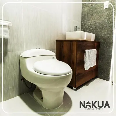 a bathroom with a white toilet and a sink at Nakua Paracas Lodge in Paracas