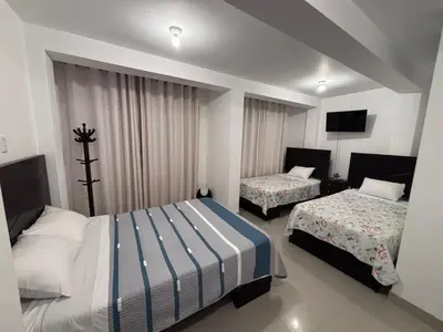 a hotel room with two beds and a television at Hotel Munay in Paracas