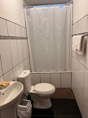 a white bathroom with a toilet and a sink at Hotel Munay in Paracas