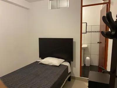 a small bedroom with a bed and a bathroom at Hotel Munay in Paracas