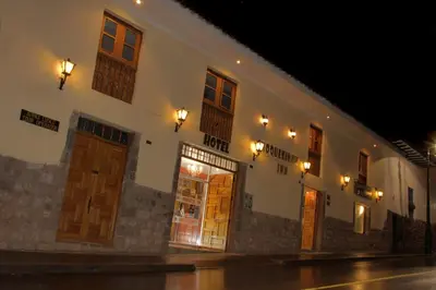 a building with doors and lights on a street at night at Hotel Choquequirao in Cusco