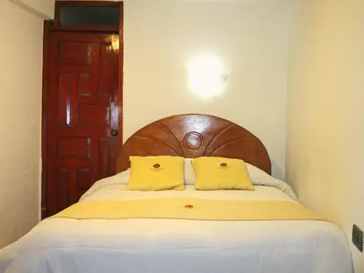 a bedroom with a bed with two yellow pillows at Hotel Choquequirao in Cusco