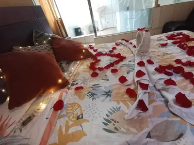 a bed with red flowers on top of it at Hostal Milagros in Chancay