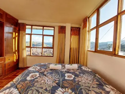 a bedroom with a bed and two windows at Casa Mirador Cristo Blanco, Great view of Cusco in Cusco