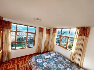 a bedroom with windows and a bed with a blue blanket at Casa Mirador Cristo Blanco, Great view of Cusco in Cusco