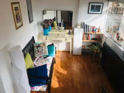 a living room with a chair and a desk and a sink at Sunny Apartment in Cusco