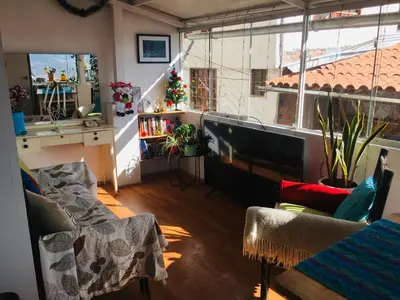 a living room with a television and a large window at Sunny Apartment in Cusco