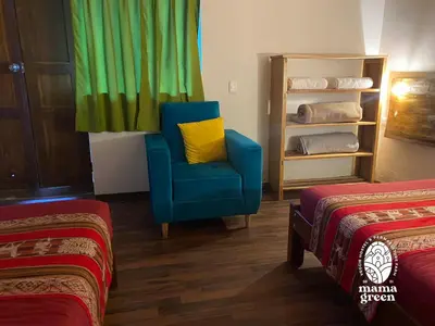 a blue chair with a yellow pillow in a room with two beds at MAMA GREEN HOSTAL - Eco Andean Experience and Permaculture Farm - Vegetarian Breakfast in Urubamba