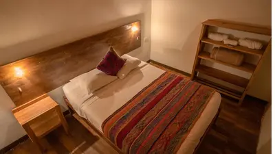 a small bedroom with a bed with a wooden headboard at MAMA GREEN HOSTAL - Eco Andean Experience and Permaculture Farm - Vegetarian Breakfast in Urubamba