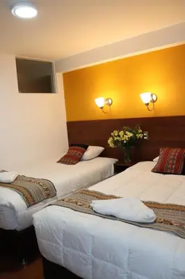two beds in a room with yellow walls at Casa del Escultor in Cusco