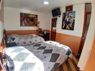 a bedroom with a bed and paintings on the wall at HOSPEDAJE CENTRAL in Ayacucho