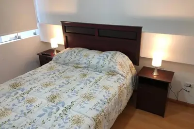 a bedroom with a bed and two night stands with lamps at 7-Departamento moderno en el área turística de Miraflores in Lima