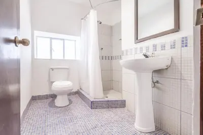 a white bathroom with a toilet and a sink at Hotel Campanario in Cusco