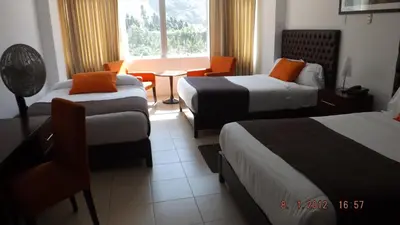 a hotel room with two beds and a table at Guizado Portillo Hacienda & Resort in Lunahuaná