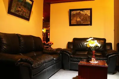a living room with two leather couches and a table with flowers at Hostal Alfredo's Palace in Cusco