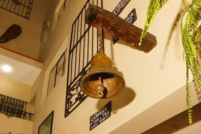 an old bell hanging from the ceiling of a building at Casa Suyay in Lima