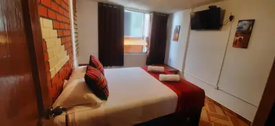 a bedroom with a bed in a room with a window at Quipu Hostal in Machu Picchu