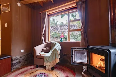 a living room with a chair and a fireplace at Unuwasi Hotel & Villa in Calca