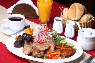 a plate of food with meat and bread and a cup of coffee at Qala Hotels & Resorts in Chincha Alta