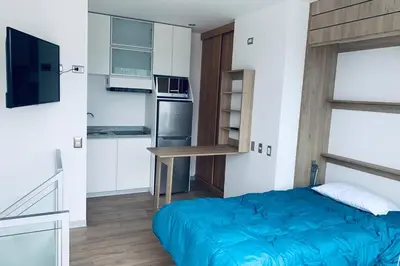 a small bedroom with a blue bed and a kitchen at Barranco Penthouse ocean boardwalk in Lima
