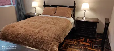 a bedroom with a bed with two night stands and two lamps at San Borja Habitación amoblada independiente dentro de departamento amoblado tipo ROOMMIE Tv42 Cerca JockeyPlaza in Lima