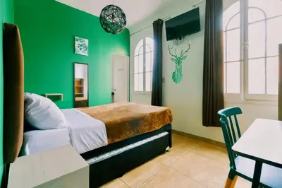 a green bedroom with a bed and a table at The Secret Garden Hostel in Lima