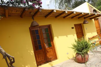 a yellow house with a wooden door and a potted plant at Hostal Loma Blanca in Ica