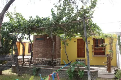a small yellow house with a tree and a playground at Hostal Loma Blanca in Ica
