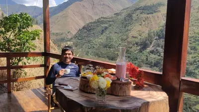 a man sitting at a table with a cup of coffee at Vertikal lodge in Santa Teresa
