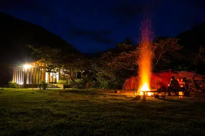 a group of people sitting around a fire at night at Vertikal lodge in Santa Teresa